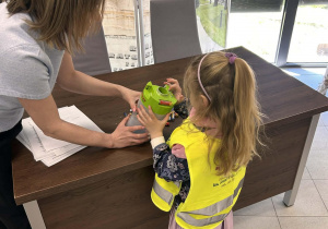 Dziewczynka wrzuca do pojemnika zużytą baterię.