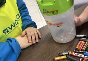 Pani objaśnia dziecku, jak działa pojemnik na zużyte baterie z testerem.