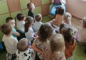 Mama czyta książkę, dzieci siedzą na dywanie