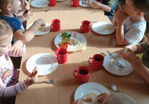 Dzieci jedzą wspólnie przy stole śniadanie