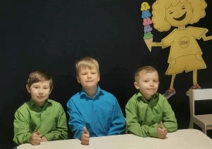 Trzyosobowa reprezentacja grupy V siedzi przy stoliku w oczekiwaniu na zadania konkursowe.
