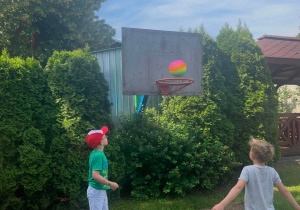 Dwóch chłopców rzucających piłkę do kosza.