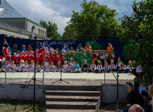 Dzieci i nuczyciele w kolorowych t-shirtach na wielkiej scenie.