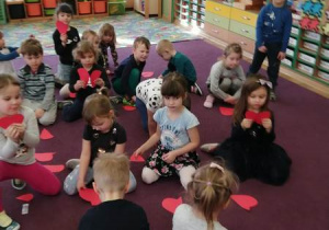 Dzieci siedzą na dywanie i składają w całość serca