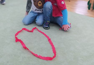 Dzieci układają serca z czerwonej bibuły