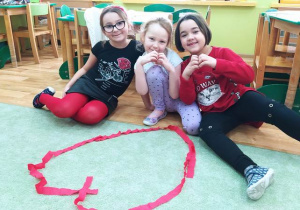 Dzieci układają serca z czerwonej bibuły
