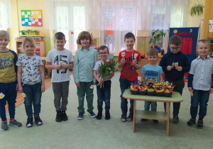 Chłopcy trzymają lizaki i kwiaty dla dziewczynek.