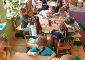 Dzieci siedzą przy stolikach i projektują odznakę przyjaciela przyrody.