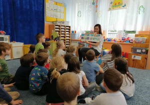 Dzieci oglądają ilustracje z książki o Koziołku.