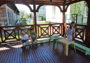 Troje dzieci siedzi w domku ogrodowym na zjeżdżalni.