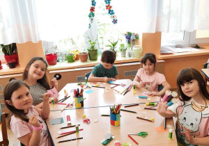 Dzieci siedzą w sali przy stolikach i wykonują paluszkowe postacie.