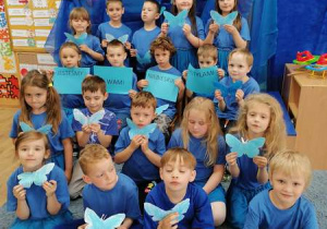 Wspólne zdjęcie dzieci z wykonanymi przez siebie niebieskimi motylami.