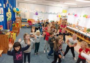 Grupa dzieci tańczy z nauczycielką przy muzyce.