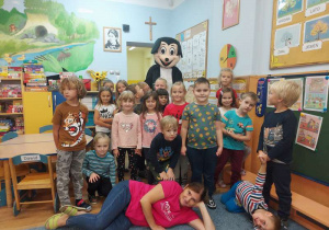 Grupa dzieci z nauczycielką pozuje do zdjęcia z Myszką Miki.