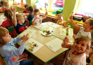 Dzieci pokazują zrobione owocowe szaszłyki.