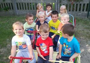Grupa dzieci siedzi w ogrodowym samochodzie
