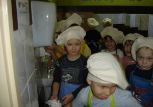 Grupa dzieci myje ręce w łazience.