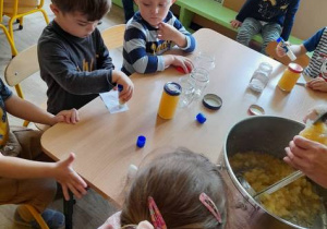 Dzieci naklejają etykiety na słoiczki z musem jabłkowym.