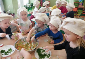 Dzieci nakładają pokrojoną surówkę do słoików.