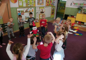 Dzieci w kole ilustrują ruchami piosenkę.