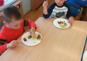 Grupa dzieci nakłada kawałki owoców na patyczki do szaszłyków