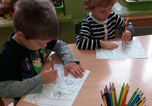 Dwóch chłopców siedzi przy stoliku i koloruje obrazek.
