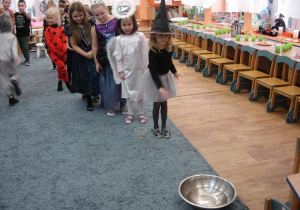 Dziewczynka w stroju czarodziejki wrzuca grosik do miski z wodą.
