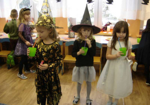 Trzy dziewczynki ( dwie Czarodziejki i Pani Zima) piją sok z zielonych kubeczków z rurkami.