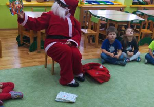Mikołaj siedzi na krześle i czyta opowiadanie o Świętym Mikołaju.