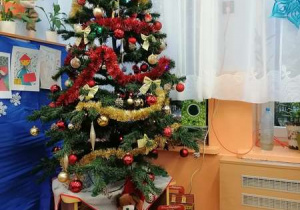 Bożonarodzeniowa choinka w naszej sali, a przed nią stoją pudełka - prezenty dla dzieci od Mikołaja.