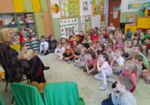 Dzieci siedzą na dywanie, aktorka inscenizuję czytane fragmenty kukiełką krasnala.