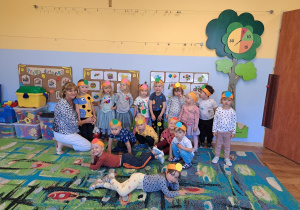 Grupa dzieci z nauczycielką – dzieci mają na głowach opaski z kolorowymi kółeczkami.