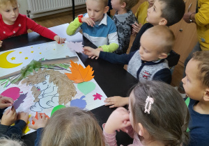 Dzieci doklejają kolorowe listki wokół jeża.