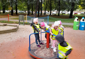 Grupka dzieci bawi się na karuzeli obrotowej.