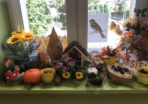 Karmnik dla ptaków stojący wśród dekoracji z darów jesieni.