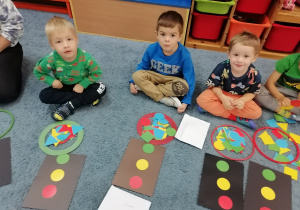 Dzieci na dywanie układają sygnalizator świetlny za pomocą figur geometrycznych.