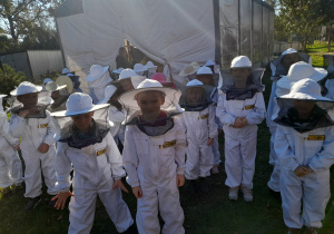 Dzieci w strojach pszczelarzy przygotowane do zajęć edukacyjnych.