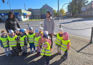 Grupa dzieci z paniami na skrzyżowaniu ulicznym