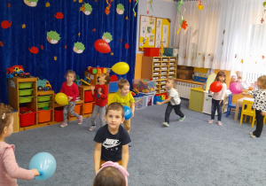 Dzieci bawią się balonami na sali.