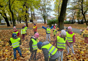 Dzieci bawią się jesiennymi liśćmi.