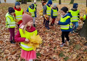 Dzieci bawią się jesiennymi liśćmi.