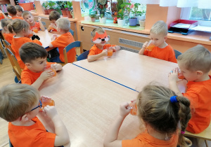 Dzieci piją sok w kolorze pomarańczowym