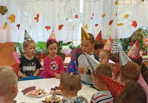 Dzieci stoją przy stoliku, na którym są słodycze.