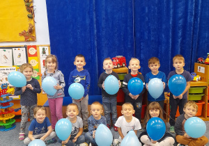 Dzieci stoją trzymając w ręce niebieski balon.