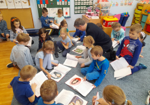 Dzieci wspólnie z autorem oglądają książki.