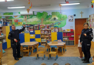 Dzieci siedzą na dywanie policjanci tłumaczą podstawowe zasady bezpieczeństwa.