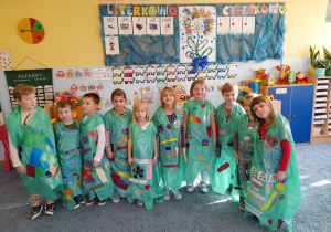 Grupa dzieci w zielonych pelerynach.