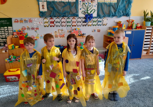 Grupa dzieci w żółtych pelerynach.