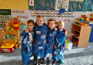 Chłopcy prezentują się w niebieskich pelerynach.