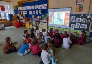 Dzieci oglądają na tablicy, jak się rysuje misia.